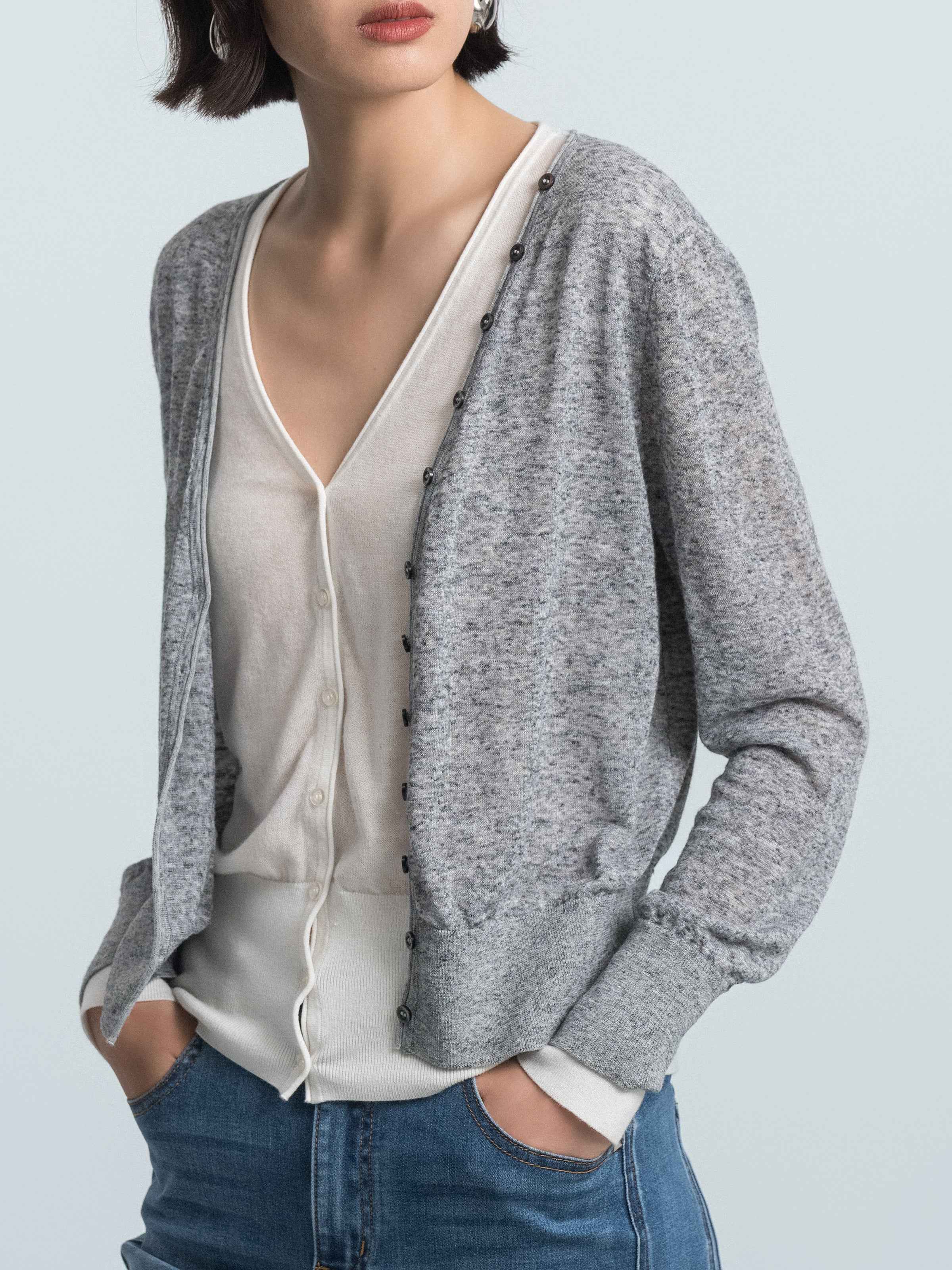 Grey knit cardigan over cream faux inner layer, V-neckline and button placket visible