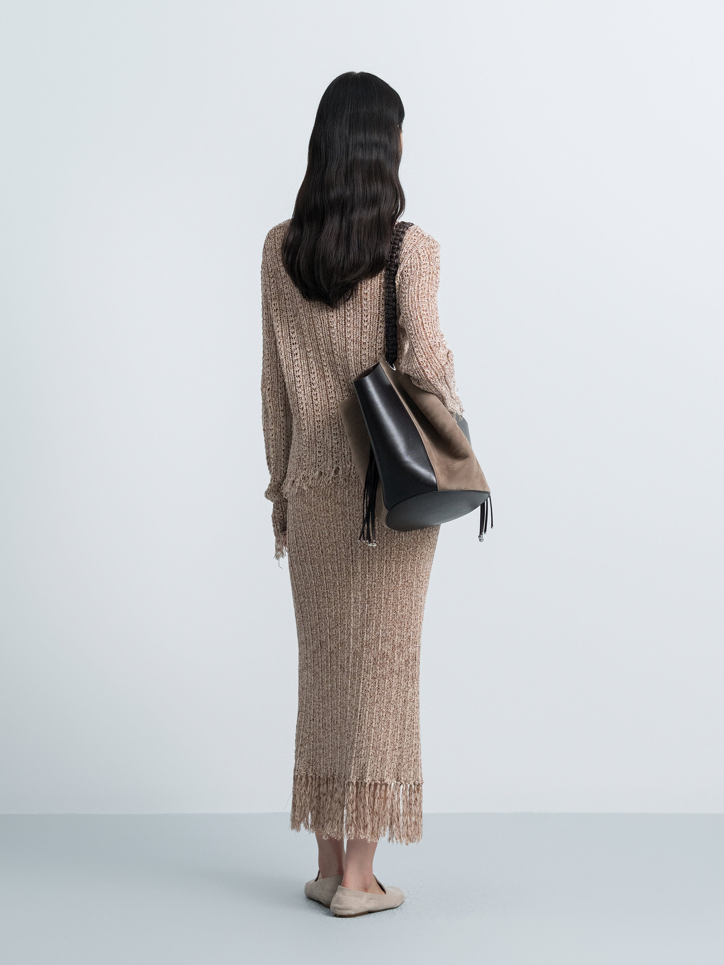 Brown hollow-out knit midi skirt from back view with long fringe hem