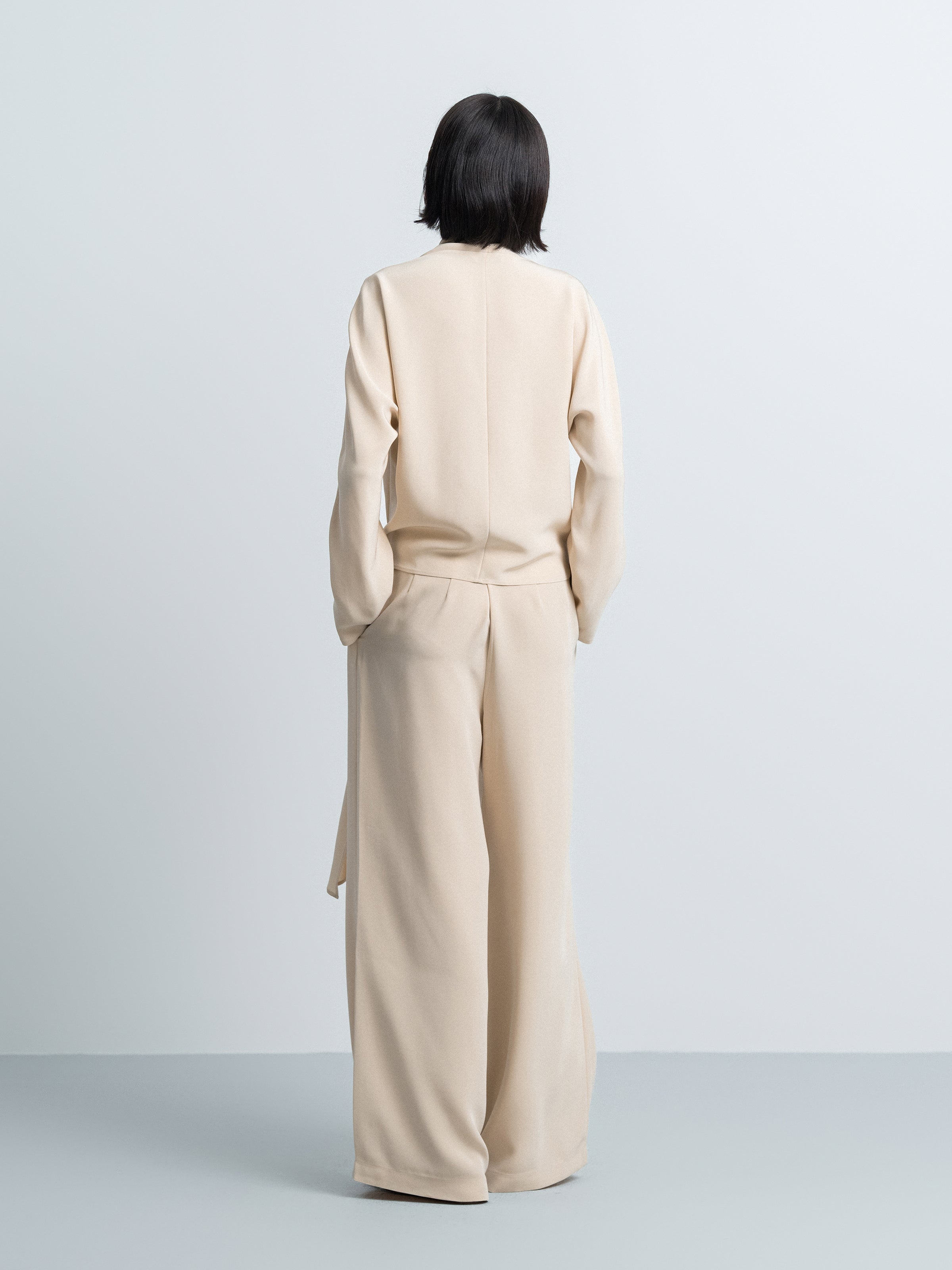 Beige satin wide-leg trousers, back view with smooth yoke and long legs.