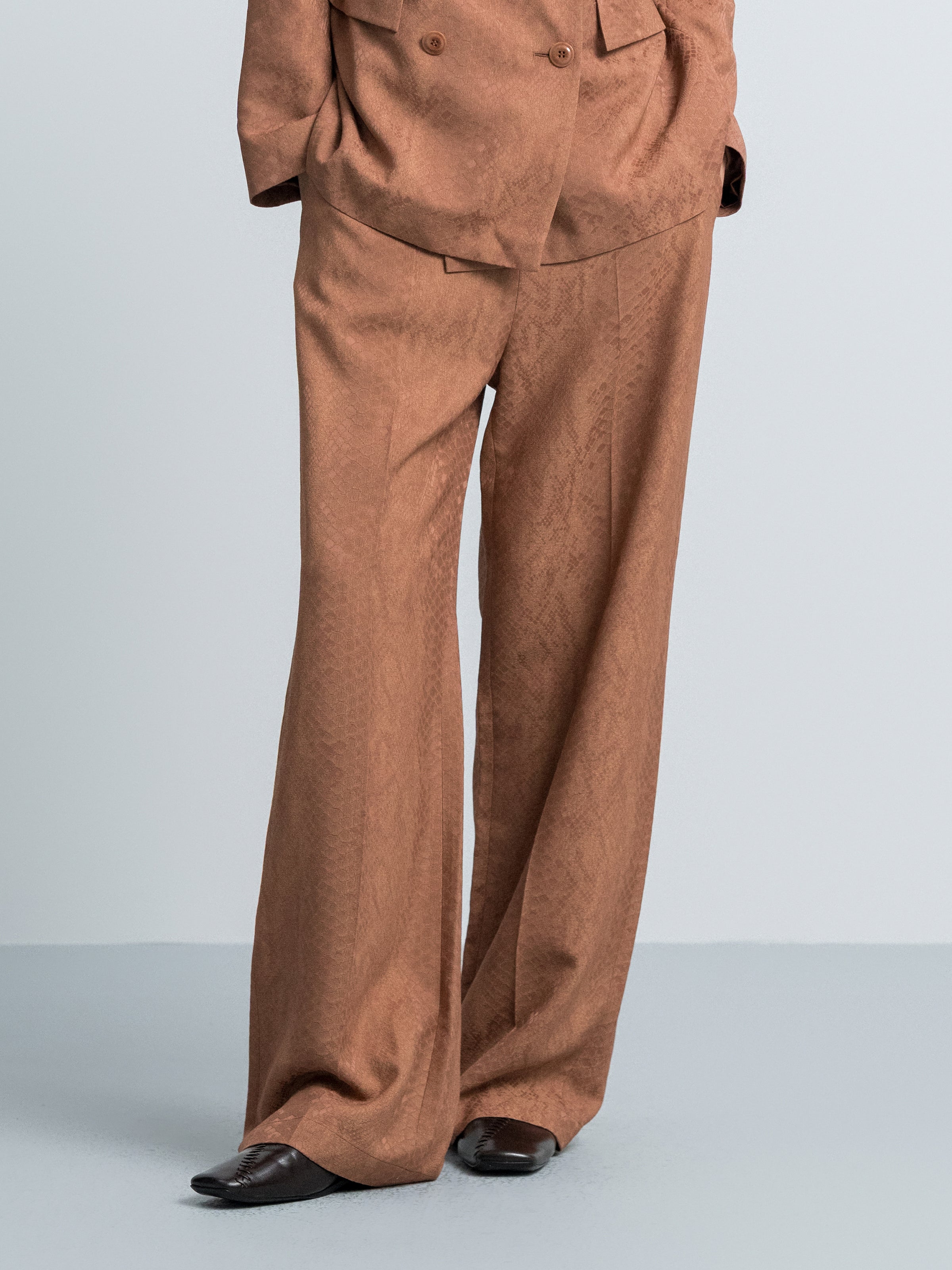 Nude brown wide-leg trousers close-up of front seams and fly