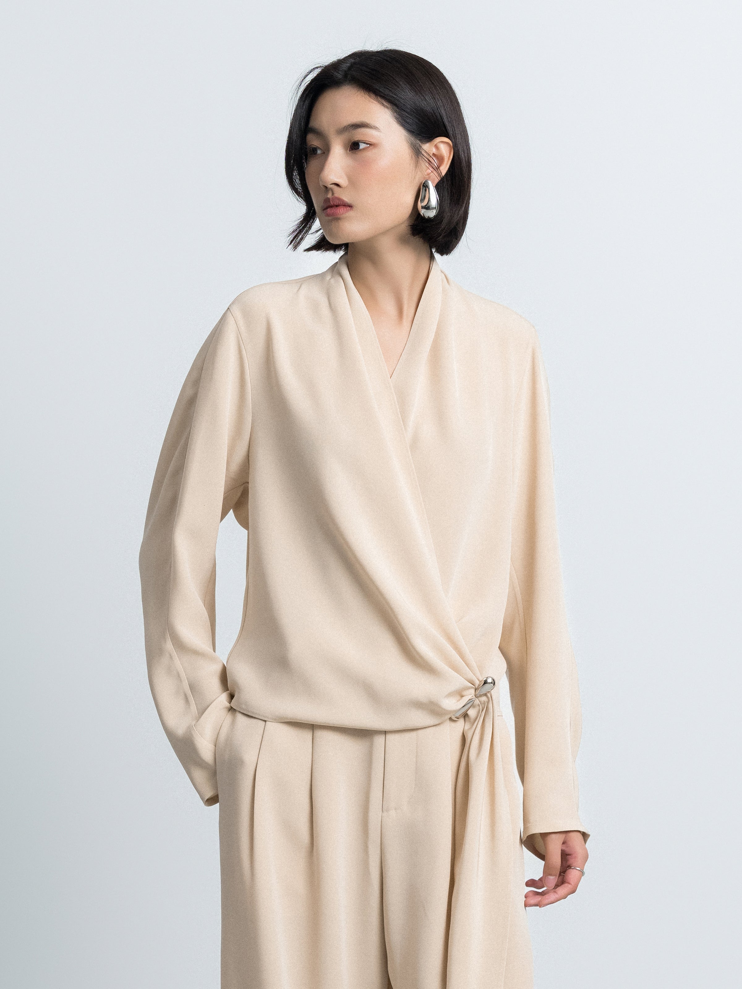 Light beige cross-over top with V-neck, long sleeves, and gathered tie at waist