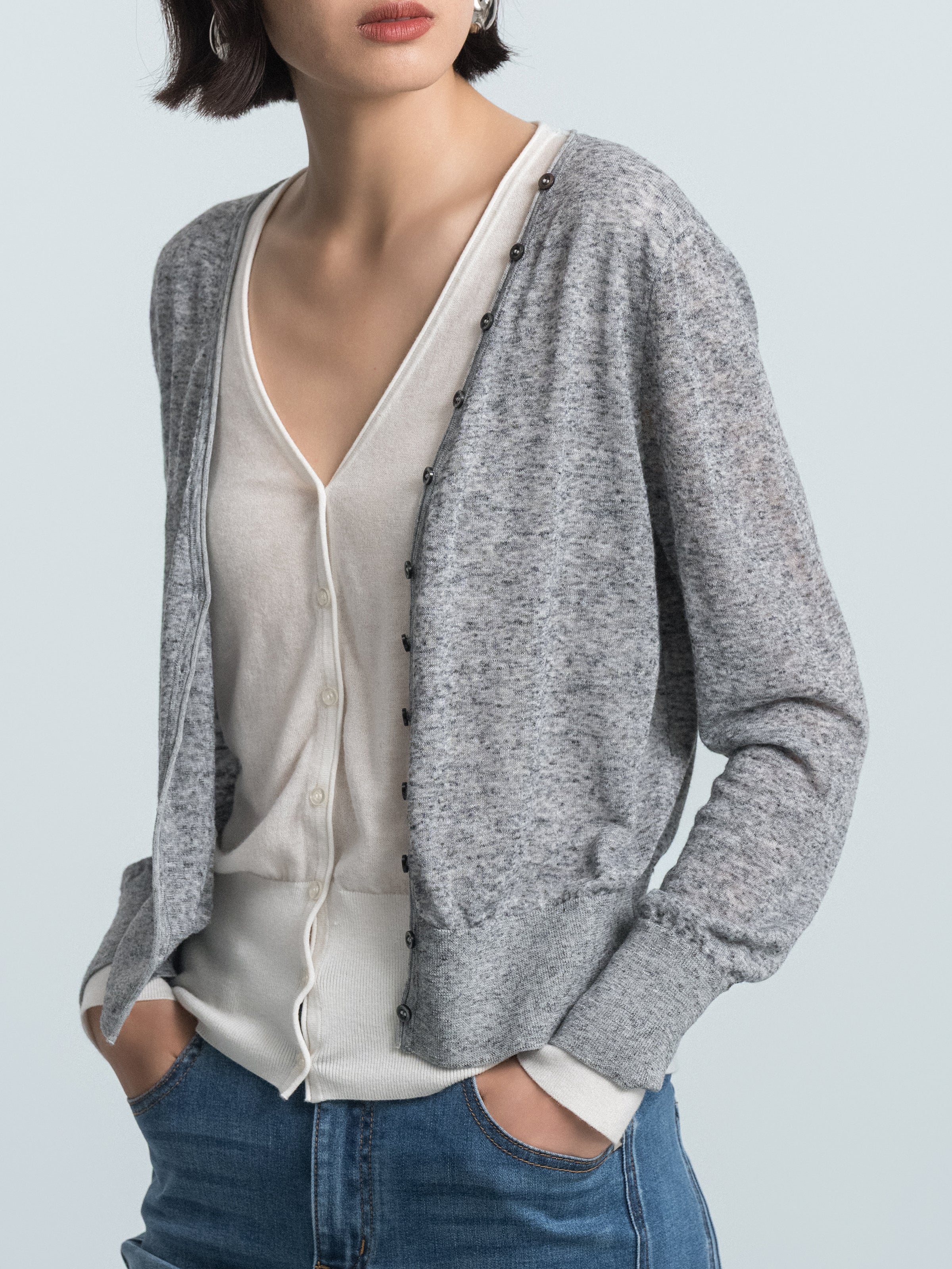 Grey knit cardigan over cream faux inner layer, V-neckline and button placket visible