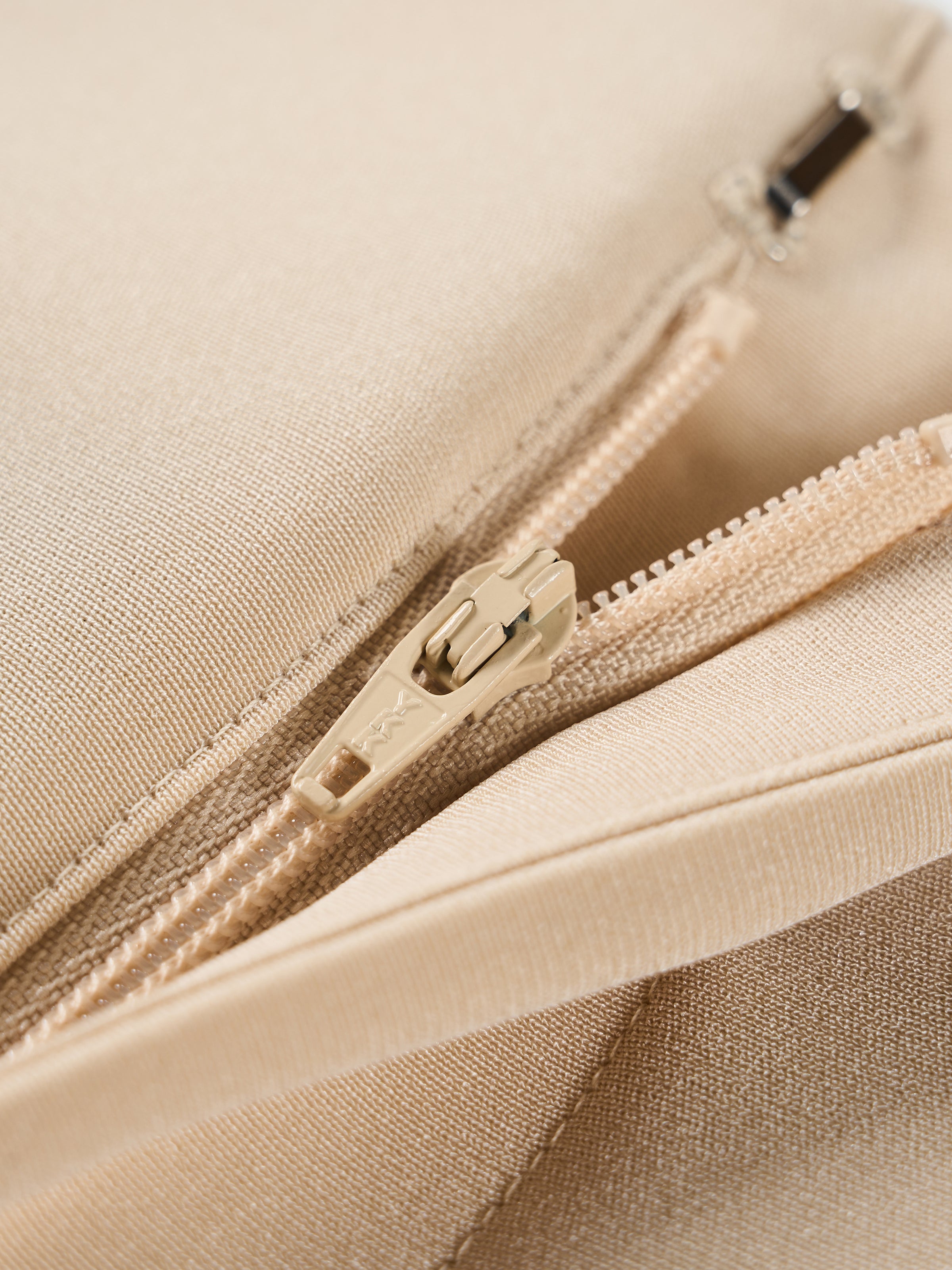 Beige satin trousers zipper and seam detail.