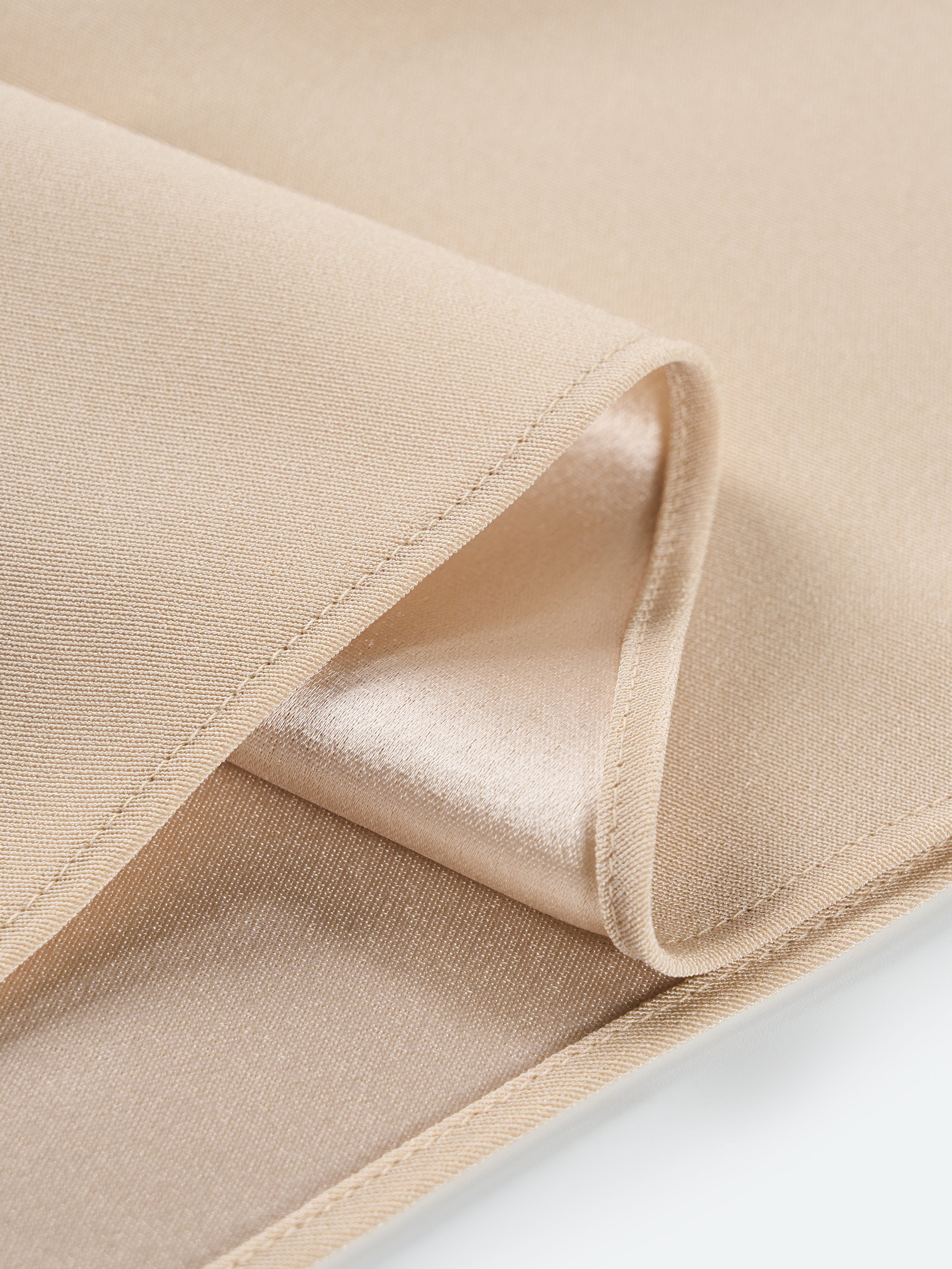 Beige yellow skirt fabric close-up with stitched fold edge