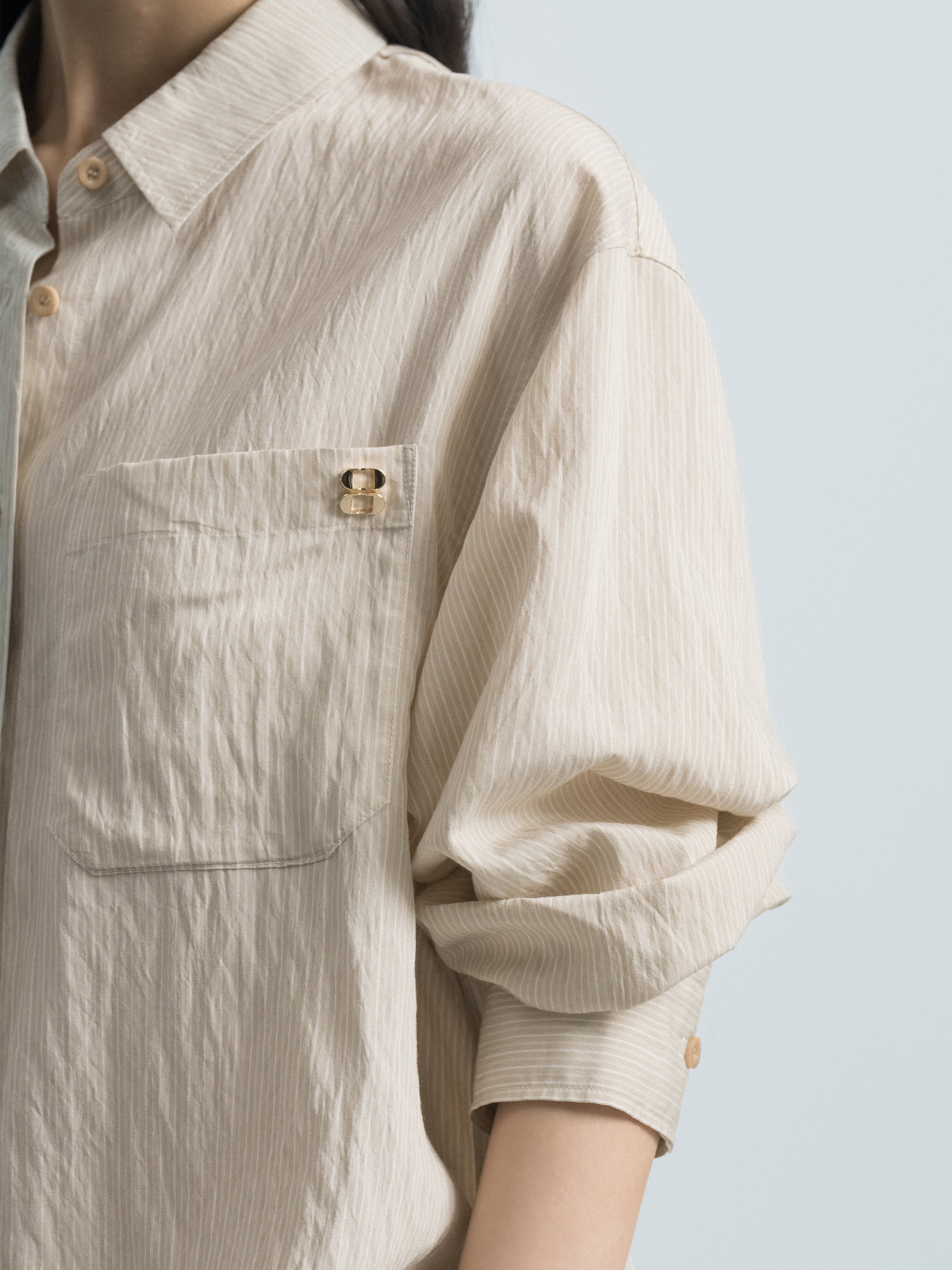 Light beige striped shirt fabric detail with chest pocket and round gold button